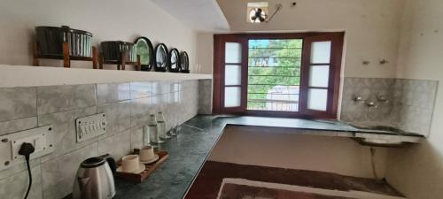 une cuisine avec un évier et une fenêtre dans l'établissement Anand Niwas Homestay Bhowali near Nainital Kainchi Dham and Bhimtal, à Bhowāli