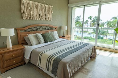 a bedroom with a large bed and a large window at Departamento Mayan Island - A pie de playa y con albercas in Acapulco