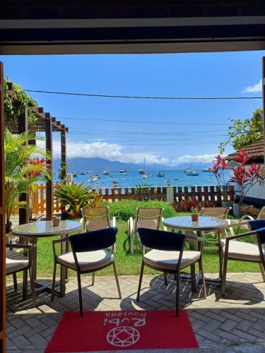 a patio with tables and chairs and a view of the ocean at Pousada Rubi in Abraão