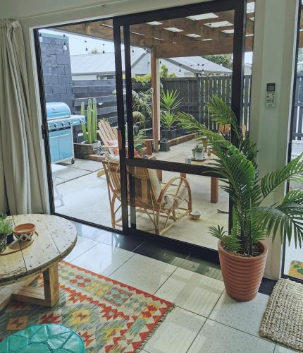 a room with a patio with a table and potted plants at Blue Moon - a Bohemian retreat at Papamoa Beach in Tauranga