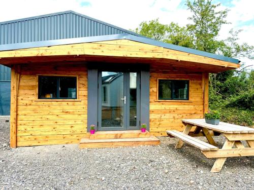 a wooden cabin with a picnic table in front of it at Cozy log cabin in Edenderry