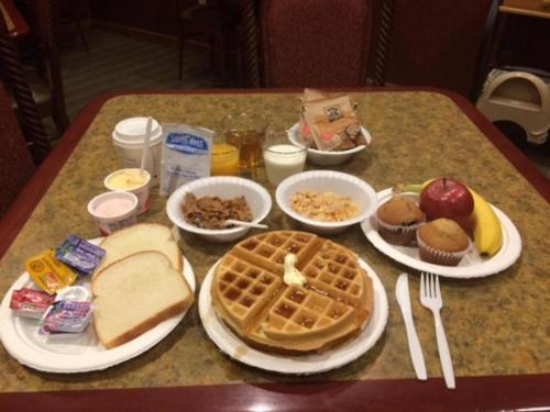 a table with plates of food and waffles and waffle at Super 8 by Wyndham Perryville in Perryville