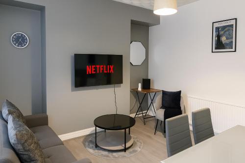 a living room with a couch and a tv on the wall at Stunning 5 Bedroom Home in the Heart of Swansea - Snooker Table, WiFi & Parking! in Swansea