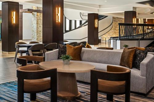 a lobby with a couch and tables and chairs at Marriott Bloomington Normal Hotel and Conference Center in Bloomington