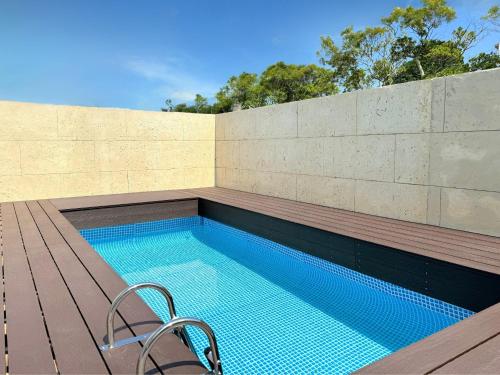 a swimming pool with a chair next to a wall at OKINAWA POOLWILLA ONNA 4A - Vacation STAY 48422v in Baba