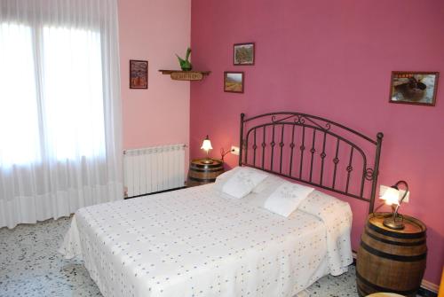 PeramolaにあるCal Serveróのピンクの壁のベッドルーム1室(白いベッド1台付)
