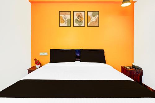 a bedroom with a large bed with an orange wall at Super Collection O Banaswadi in Bengaluru