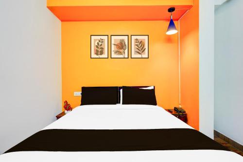a bedroom with a bed with an orange wall at Super Collection O Banaswadi in Bengaluru