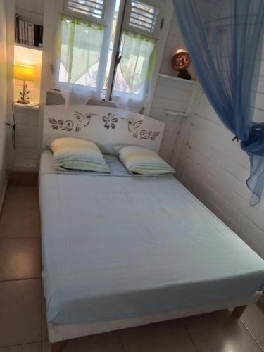 a bed in a tiny house with a window at Le Jardin aux Oiseaux in Sainte-Anne