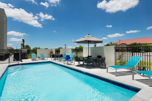 a swimming pool with chairs and an umbrella at TownePlace Suites Brownsville in Brownsville