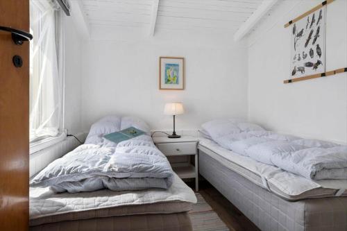 a bedroom with two beds and a nightstand with a lamp at 20508-Samso-Onsbjerg-Vestermark-63 in Sælvig