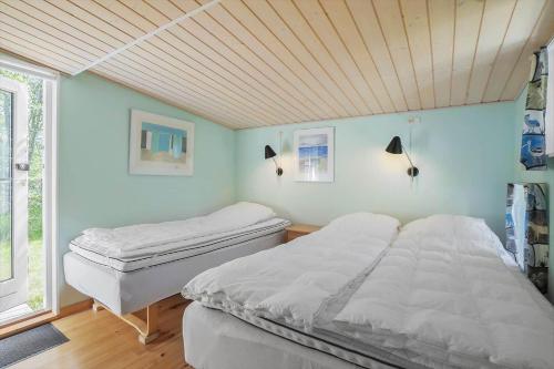 a bedroom with two beds and a wooden ceiling at 20399-Samso-Laerkevej-24 in Nordby