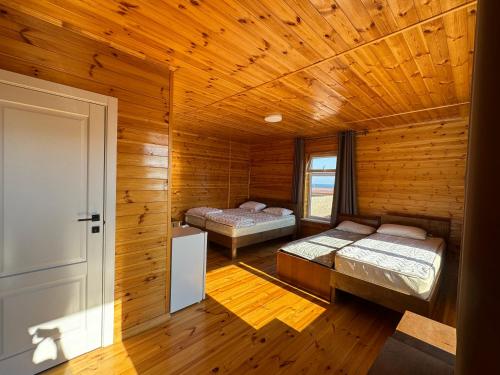 a bedroom with two beds in a wooden cabin at Cloud Guest House in Cholpon-Ata
