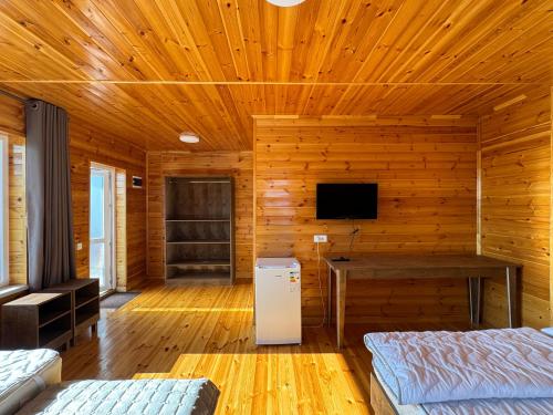 a wooden room with two beds and a television at Cloud Guest House in Cholpon-Ata