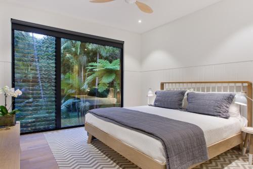 een slaapkamer met een bed en een groot raam bij Luxury rainforest retreat, Little Cove in Noosa Heads