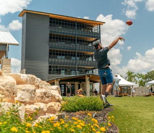 a man throwing a football in front of a building at Resort at Fredericksburg Unit 4 in Rocky Hill