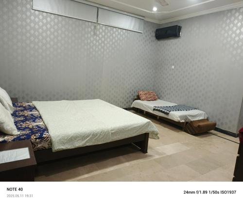 a bedroom with two beds and a tv on the wall at Secret Garden in Islamabad