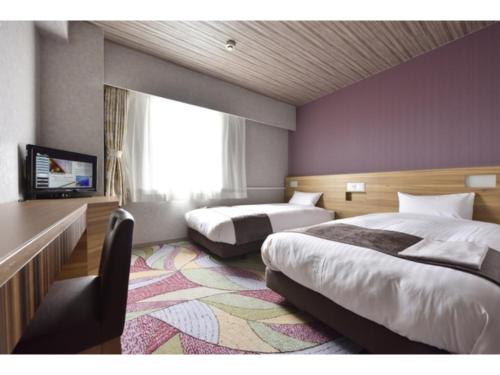 a hotel room with two beds and a tv at Smile Hotel Kushiro - Vacation STAY 10575v in Kushiro