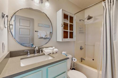 Un baño con lavabo, espejo e inodoro. en Bayview 67, en Orange Beach