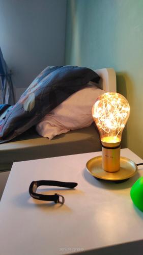 a lamp on a table next to a bed at Suite familiale de 2 chambres toutes équipées 4 personnes maximum in Traînou