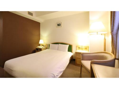 a hotel room with a white bed and a chair at Smile Hotel Nagoya Shinkansenguchi - Vacation STAY 05091v in Nagoya