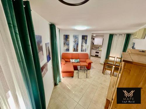 a living room with an orange couch and a kitchen at Mape Loft Rural El MIMBRAL in Algar