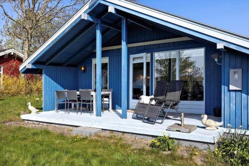 a blue house with chairs and a table on a deck at AE311-Aeroskobing-Hanses-Ager-11 in Ærøskøbing