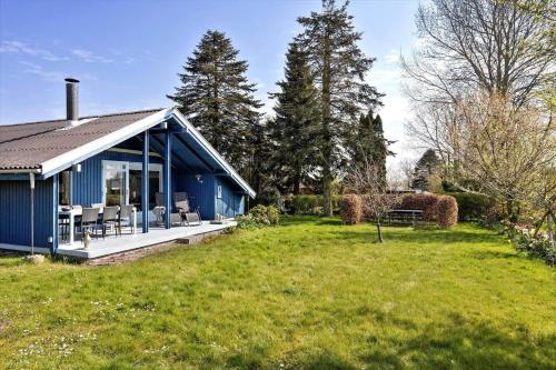 a blue house in a field with chairs and trees at AE311-Aeroskobing-Hanses-Ager-11 in Ærøskøbing