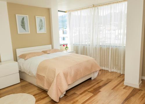 a bedroom with a bed and a large window at Bienvenue chez nous in Otavalo