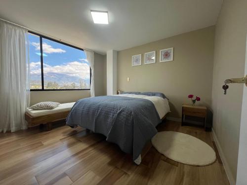 a bedroom with a bed and a large window at Bienvenue chez nous in Otavalo