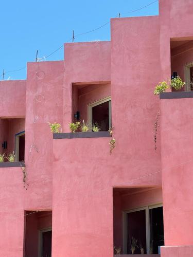 a pink building with potted plants on the windows at Laiva Hotel San Jose by Tasman in San José del Cabo