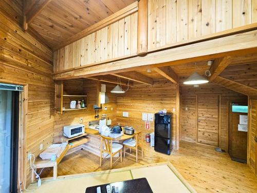 a kitchen with wooden walls and a table and a refrigerator at Washiki Shiki no Sato Cottage - Vacation STAY 03104v in Wajiki