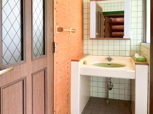 a bathroom with a sink and a mirror and a door at Washiki Shiki no Sato Cottage - Vacation STAY 03146v in Wajiki