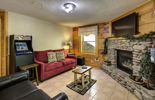 a living room with a red couch and a fireplace at Best Value Cabin Hot Tub Arcade Close to Strip in Pigeon Forge