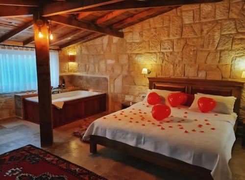 a bedroom with a bed with red pillows and a tub at Yıldız Hotel in Urgup