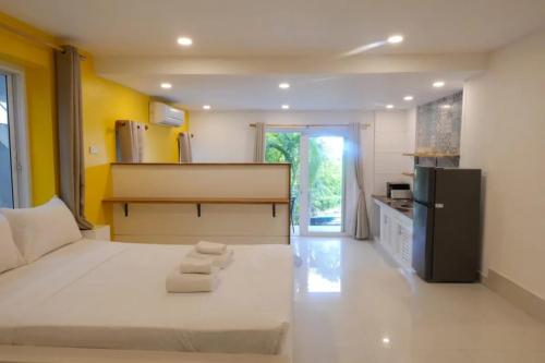 a bedroom with a large white bed and a kitchen at Modern Studio Apartment Shared Pool in Koh Samui 
