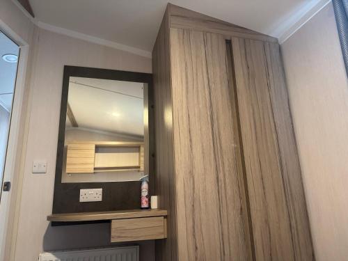 a bathroom with a mirror and a wooden cabinet at 3 bedroom Caravan Manor Park Free WiFi , Linen not included , Pets stay free in Hunstanton