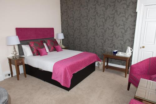 a bedroom with a large bed with a pink blanket at Links Hotel in Montrose