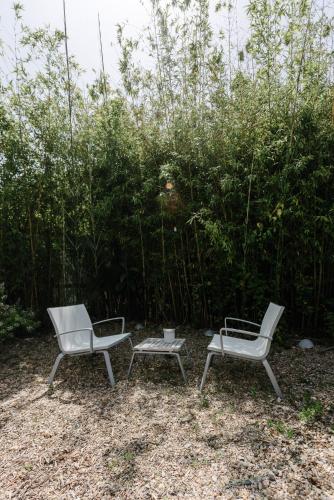 three chairs and a table in front of a bush at Quinta Do Miguel in Aldeia do Meco