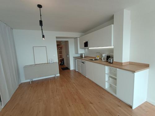 a kitchen with white cabinets and a wooden floor at LOFT ROYAL - apartamento "loft" con terraza y vistas al mar in Faro de Cullera