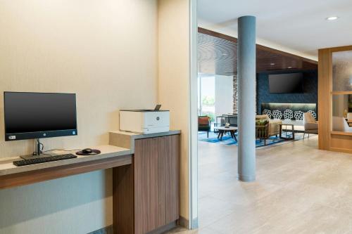 a room with a desk with a computer and a living room at Fairfield Inn & Suites Hanford in Hanford