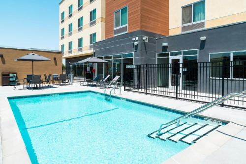 a swimming pool in a courtyard with a building at Fairfield Inn & Suites Hanford in Hanford