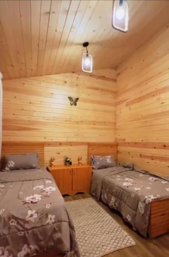 a bedroom with two beds in a log cabin at اكوخ في مزرعة بساتين اللوز in Quai