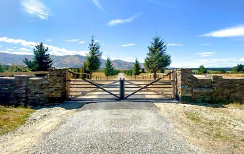 a gate on a road with mountains in the background at Te Awa Lodge Riverside retreat in Wanaka