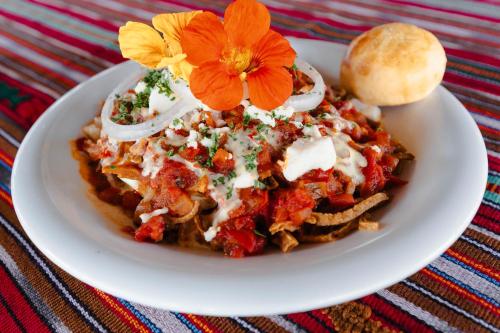 a white plate with a pasta dish with tomato sauce and cheese at Hotel Toliman in San Lucas Tolimán