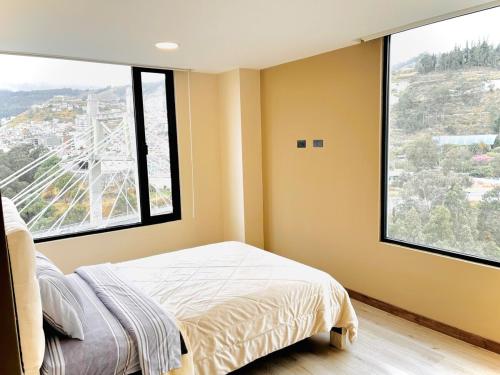 a bedroom with a bed and two large windows at Air Stay in Ambato