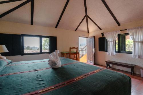 a bedroom with a large green bed with windows at Hotel Toliman in San Lucas Tolimán