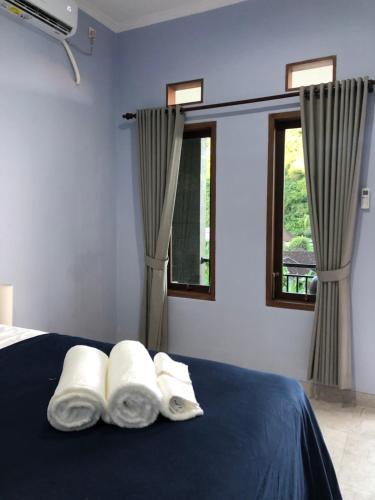 a bedroom with a bed with three pillows and two windows at Naomi Homestay in Padangbai
