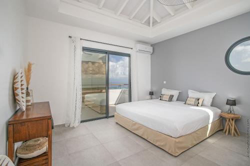 a white bedroom with a bed and a balcony at Villa de luxe vue exceptionnelle - MQDI92 10p in Le Diamant