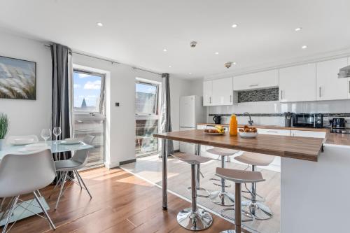 a kitchen with white cabinets and a wooden table and stools at Fabulous Stays Perfect Long in City Centre Stay Smart Tv Each Room FREE WiFi AND Parking in Nottingham